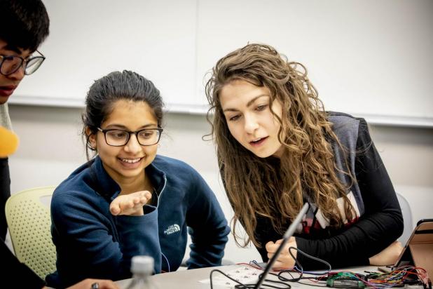 Two students sitting looking at electronics