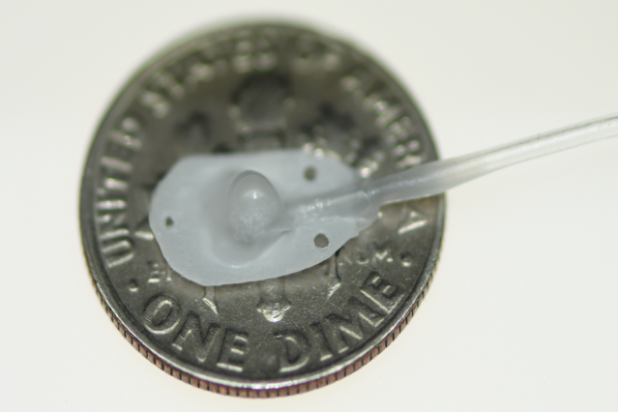 *Photo: Therepi’s reservoir, which would attach directly to the damaged heart tissue, is placed on a dime for size reference and connected to a self-sealing subcutaneous port by Whyte, et al./Nature Biomedical Engineering